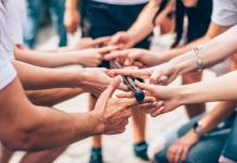 Hände verschiedener Personen halten gemeinsam einen Stab als Teamevent